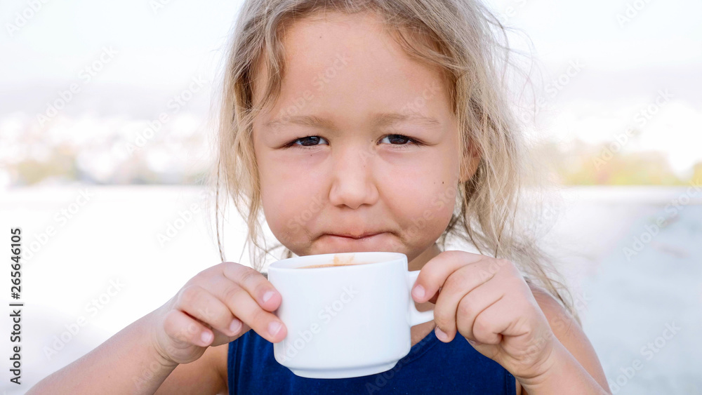 Portrait of little blonde girl is drinking hot chocolate from the white cup. Portrait of little blonde girl is drinking hot chocolate from the white cup.