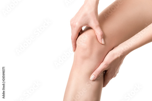 Female injured knee joint. Woman suffered her leg and touches her sore spot by hands. Well groomed skin  close up  isolated on white