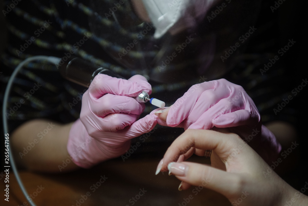 Manicurist makes hardware manicure close-up. Treatment of nails with the help of hardware manicure
