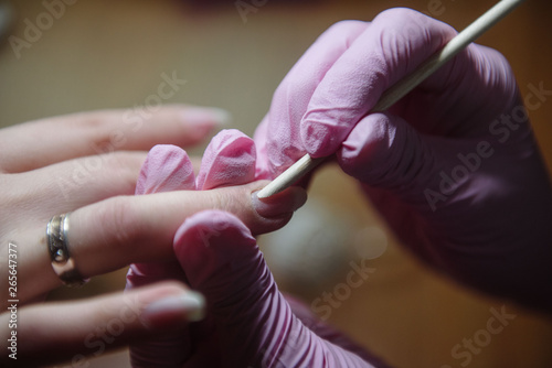 Manicurist makes a hygienic manicure with the help of an orange stick close-up