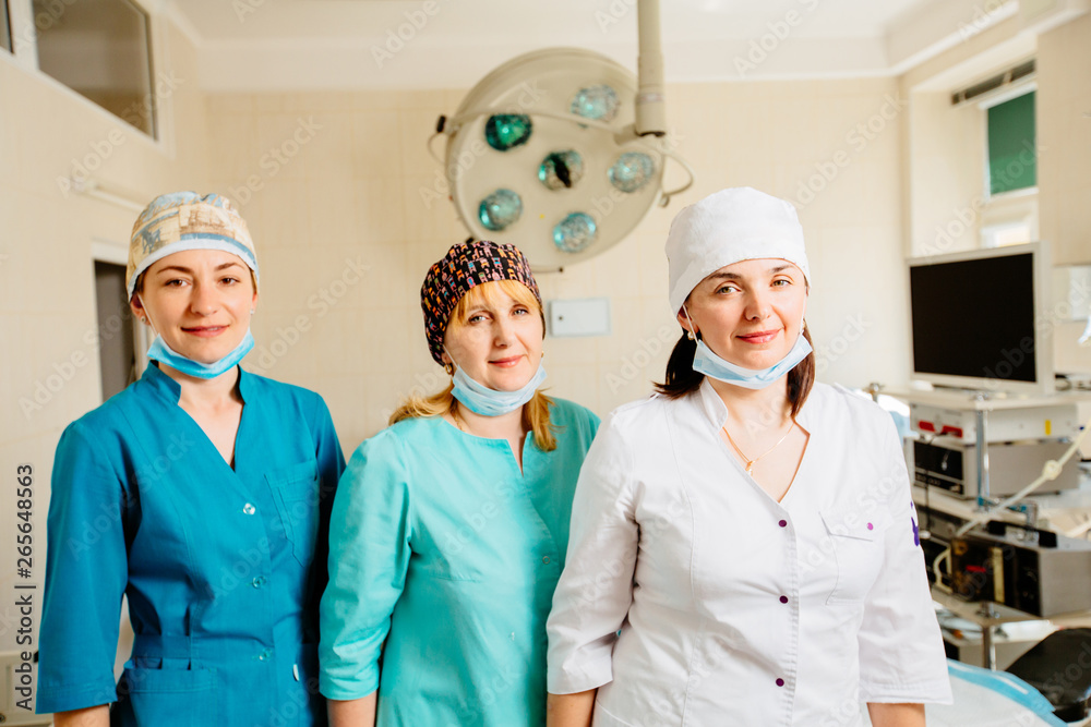 Portrait of three beautiful female surgical team members standing in operating theatre.