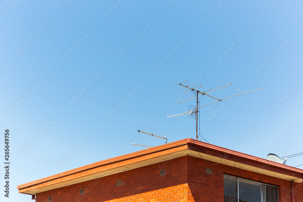Analogue tv antennas perched on top of red retro brick house. Analogue tv antennas perched on top of red retro brick house.