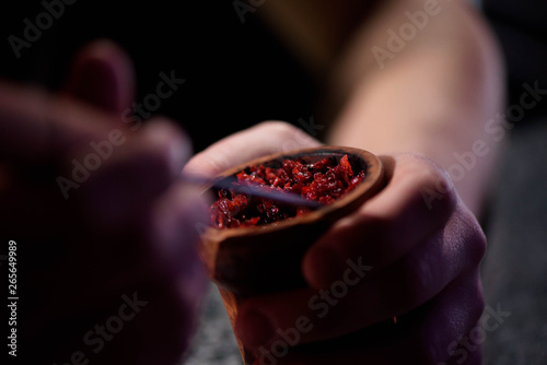 Barman fills black burnt ceramic bowl for hookah smoking different types of tobacco. photo