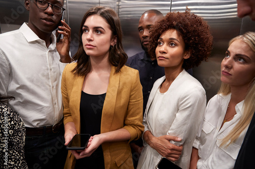 Work colleagues standing in an elevator at their office, close up photo