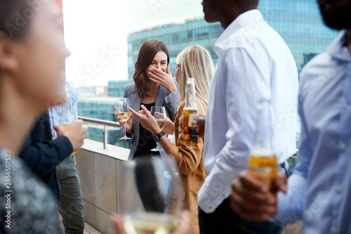 Office colleagues socialising with drinks on a balcony in the city after work photo