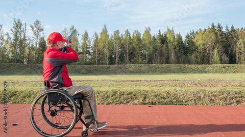 disabled person in a wheelchair shoots skeet, clay pigeon shooting in a weapons club, banner concept