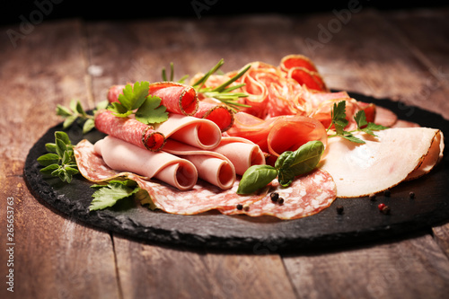 Food tray with delicious salami, pieces of sliced ham, sausages,salad and vegetable. Meat platter with selection