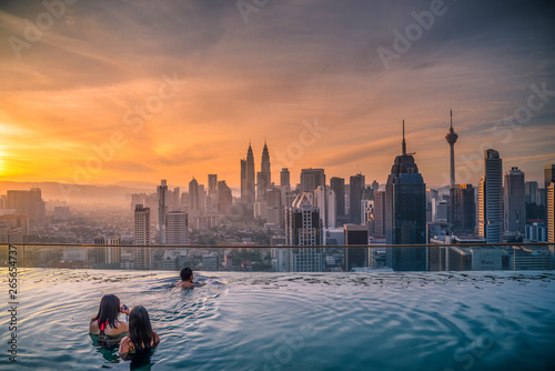 Traveler looking view skyline Kuala Lumpur city in swimming pool on the roof top of hotel at sunrise in Kuala Lumpur, Malaysia.