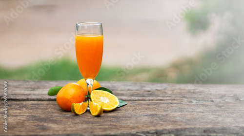 orange juice in a glass and ripe sliced orange on dark old wooden table, copy space 