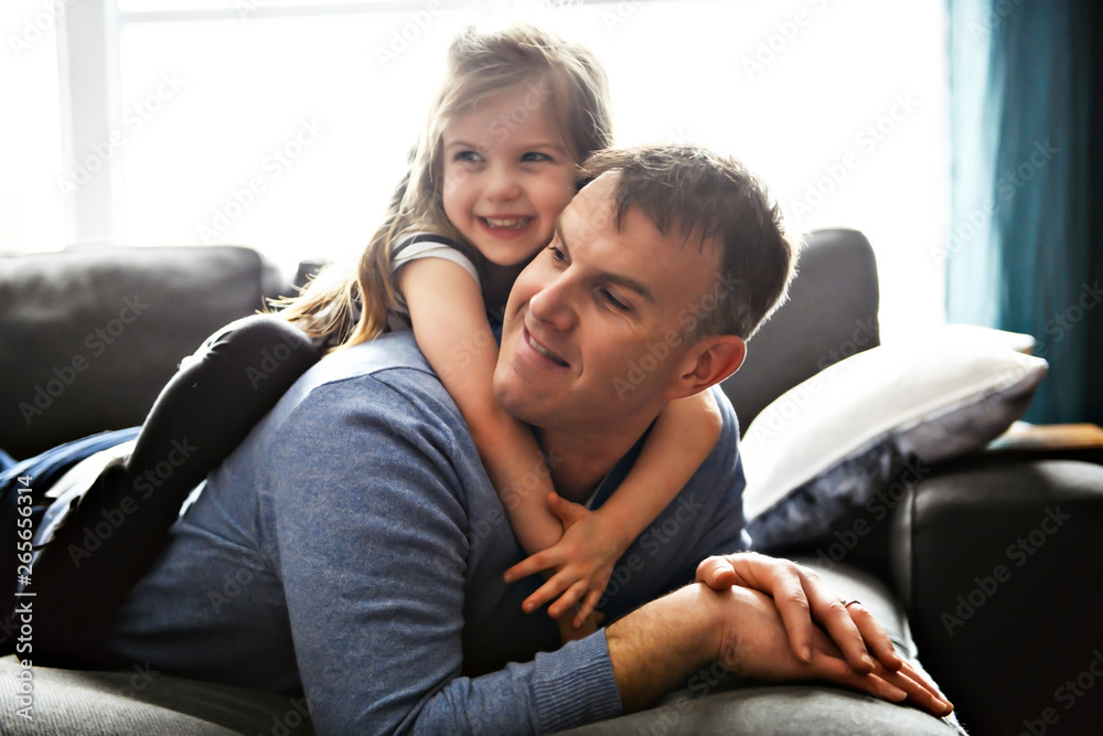 A nice and cool child girl sitting on father on the living room A nice and cool child girl sitting on father on the living room