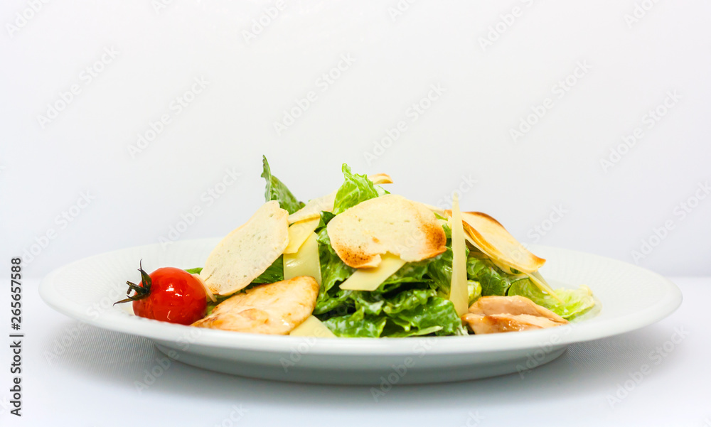 Caesar salad with croutons, cheese, lettuce and pickled tomatoes on a white background general view