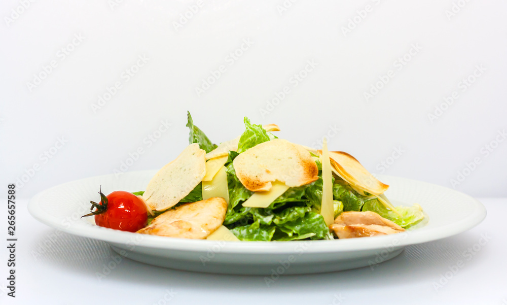 Caesar salad with croutons, cheese, lettuce and pickled tomatoes on a white background general view Caesar salad with croutons, cheese, lettuce and pickled tomatoes on a white background general view