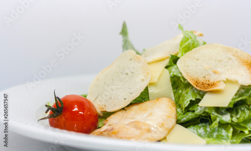 Caesar salad with croutons, cheese, lettuce and pickled tomatoes on a white background close-up