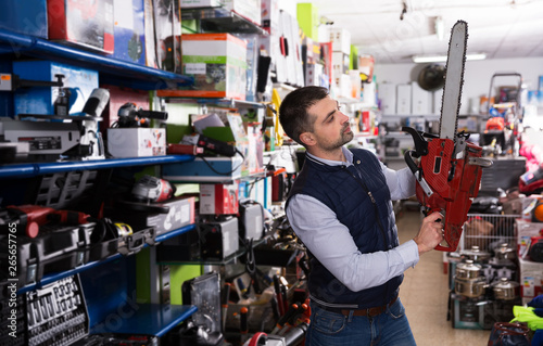Man choosing chainsaw in store
