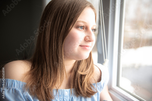 Portrait of a beautiful young teenager girl near window