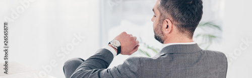 panoramic shot of businessman looking at watch and checking time