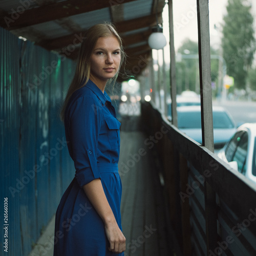 Beautiful blond hair girl posing in blue shirt at the city