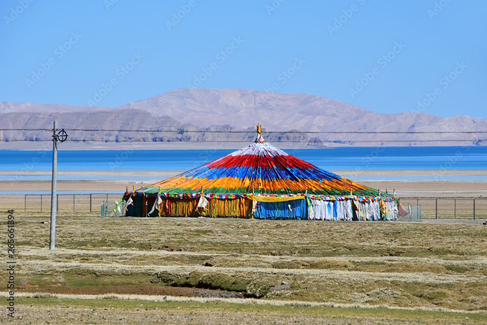 China, Tibet. Construction with colorful flags with mantras, indicating a place of power and worship, on the shore of lake Selling