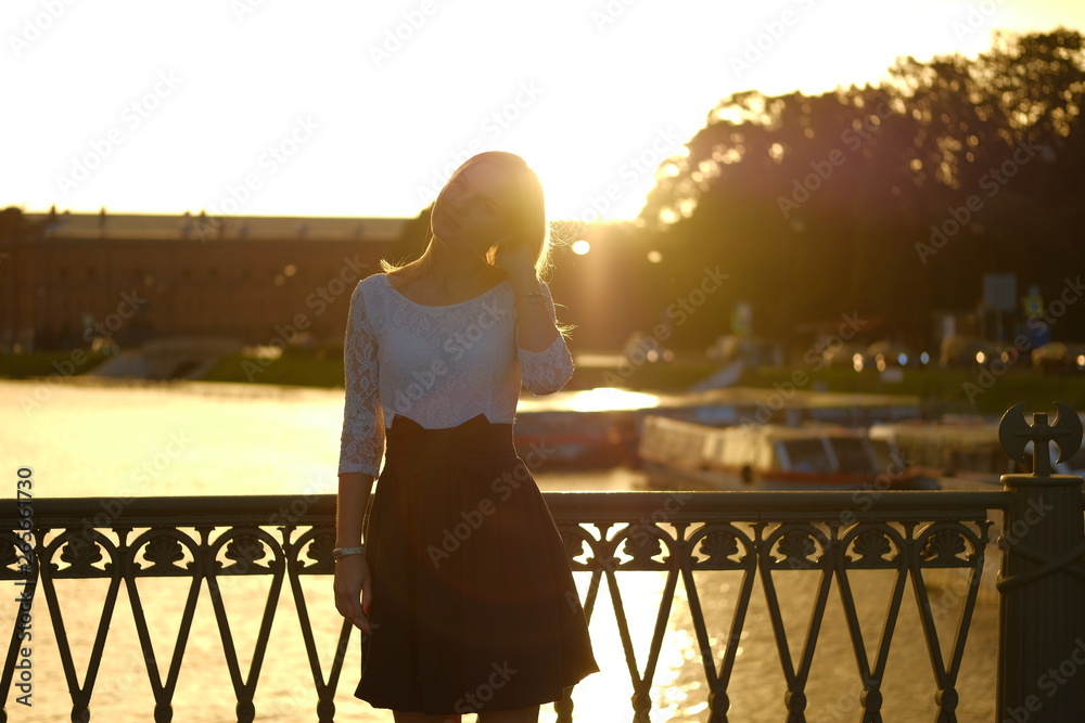 Beautiful blond girl in dress posing for photo at sunset