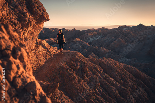 Woman hiking through the mountains of Atacama desert during sunset photo