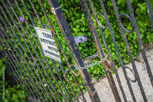 Gate closed with a chain , with a plaque saying 'private property no trespassing' in polish