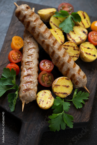 Closeup of grilled chicken kebabs with roasted potato, cherry tomatoes and fresh parsley, selective focus