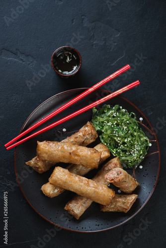 Plate with traditional vietnamese fried spring rolls or nems, flatlay on a black stone background, studio shot photo