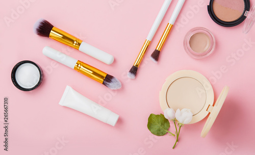 Face care and make up products with spring apple bloom (tonic or lotion, serum, cream, micellar water, cotton pads and makeup brushes) on pink background. Freshness and face care. Decorative cosmetics