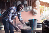 African man standing to blow fire to cook rice