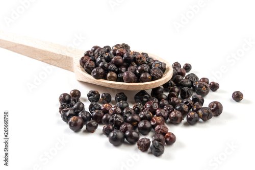 juniper berries on wooden spoon on white background