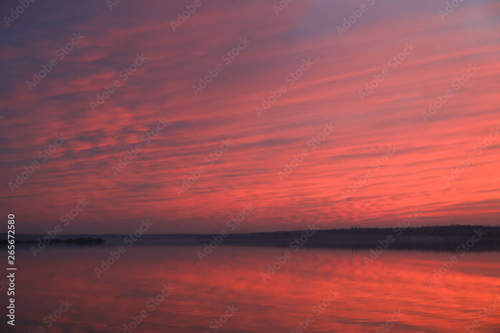 Dramatic sunset sky background with river, fiery clouds, yellow, orange and pink colour, nature background. Beautiful skies