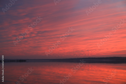 Dramatic sunset sky background with river, fiery clouds, yellow, orange and pink colour, nature background. Beautiful skies