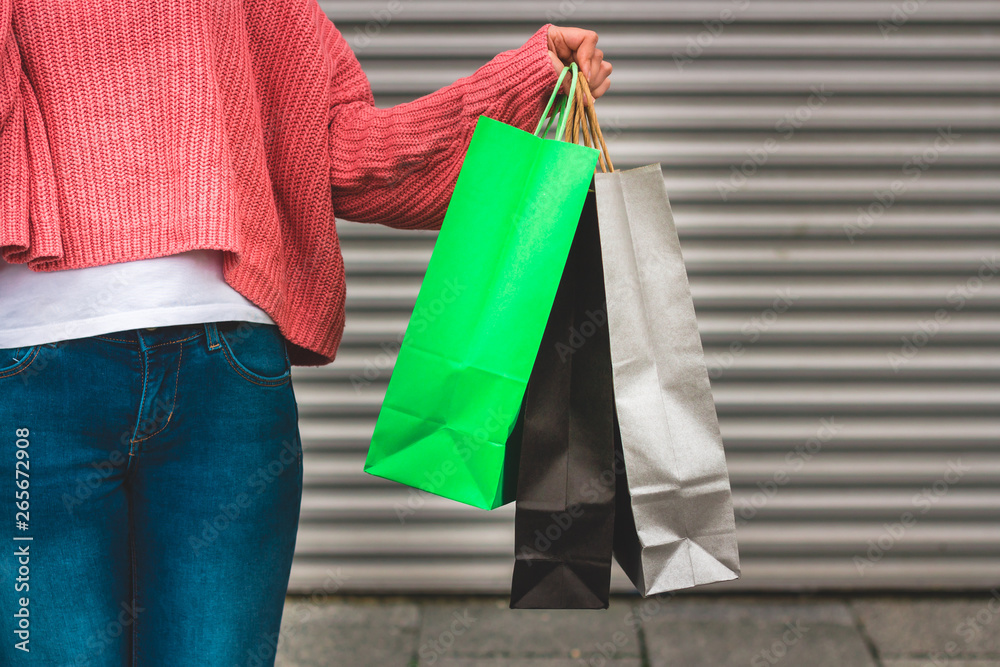 Woman wearing jeans and pink blouse holding multiple paper shopping bags – Modern and stylish female carrying her bags - Concept image for wealthy lifestyle and marketing Woman wearing jeans and pink blouse holding multiple paper shopping bags – Modern and stylish female carrying her bags - Concept image for wealthy lifestyle and marketing