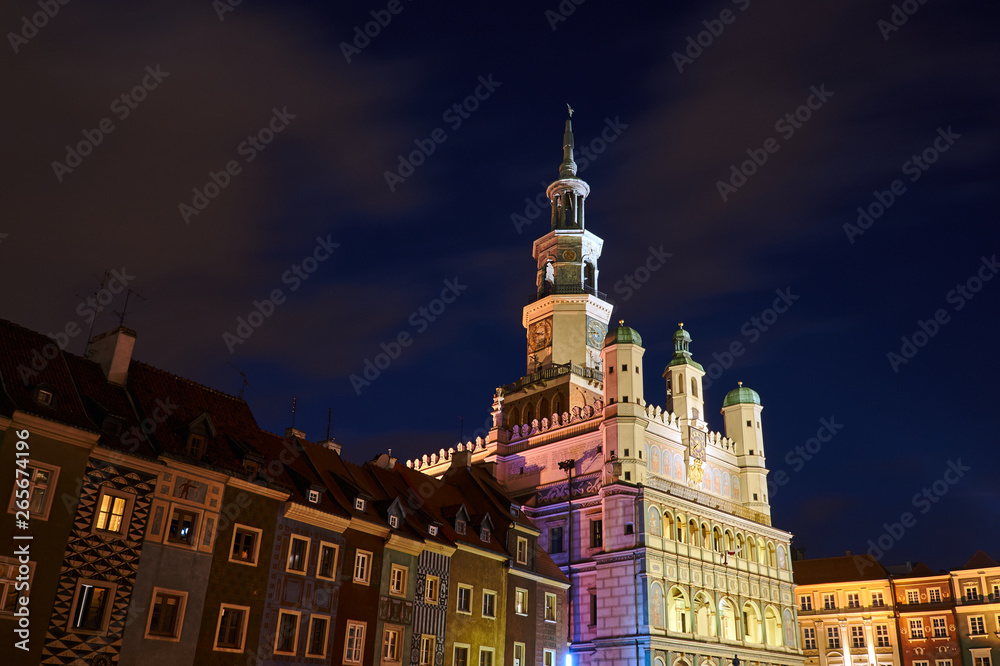 Historic tenement houses and the Renaissance town hall with a tower at night in Poznan.