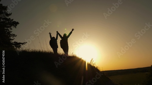 family mom and daughter travel vacation. Woman with raised hands on top of mountain looking at sunset. Hiker Girl raising her hand up, celebrating victory and enjoying beautiful scenery and nature.