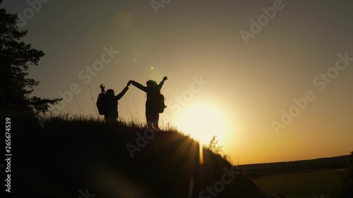 family mom and daughter travel vacation. Woman with raised hands on top of mountain looking at sunset. Hiker Girl raising her hand up, celebrating victory and enjoying beautiful scenery and nature.
