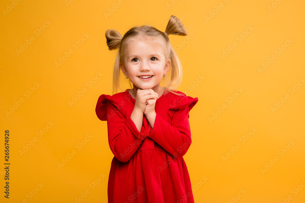 baby girl portrait isolate yellow background.Stylish little baby with hands up. Portrait of shocked little girl in red dress isolated on yellow background 