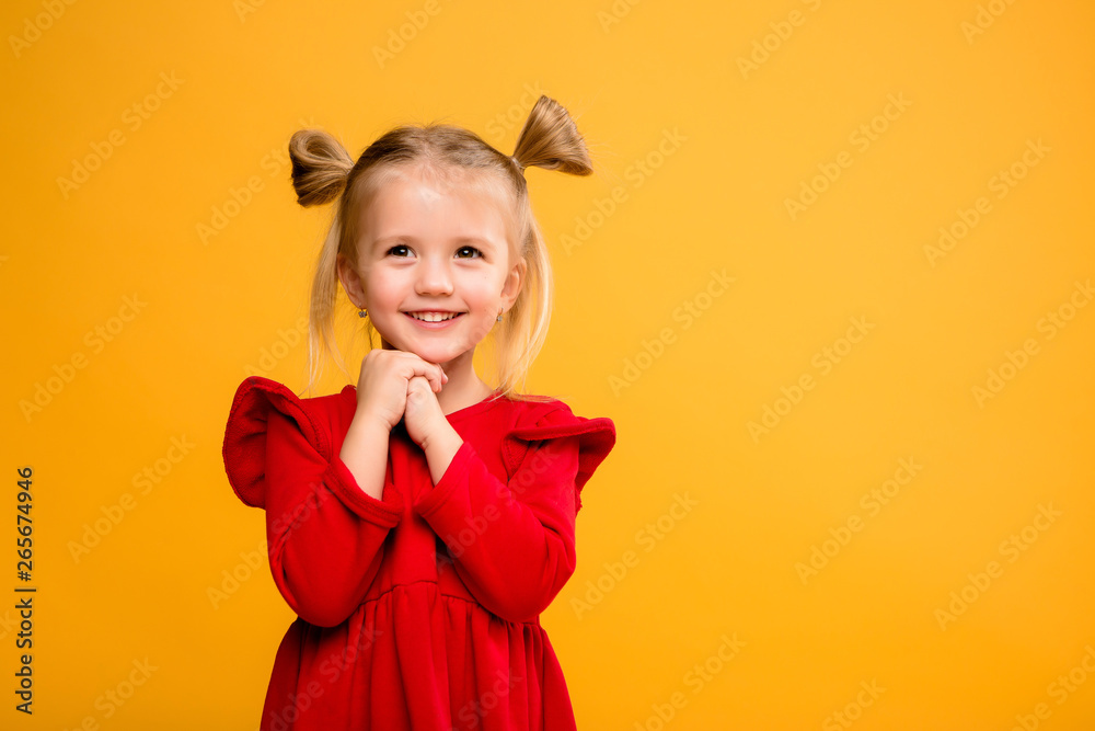 baby girl portrait isolate yellow background.Stylish little baby with hands up. Portrait of shocked little girl in red dress isolated on yellow background 