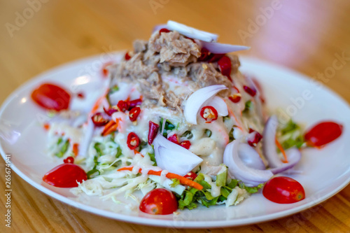 Spicy tuna salad In a white plate, salad this dish consist of tuna, lettuce, chinese cabbage, carrot onion red chilli rough cut, dressing and tomato half cut Used to arrange dishes.