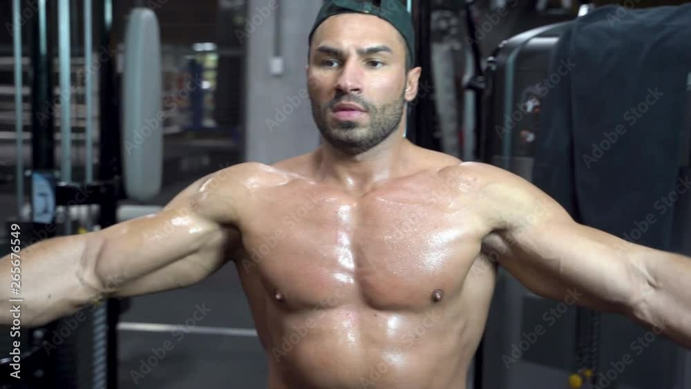 Muscular bodybuilder handsome man with a naked torso doing exercises in gym. Muscular bodybuilder handsome man with a naked torso doing exercises in gym.