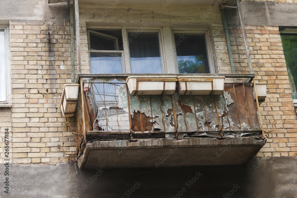 balcony in disrepair and collapsing on the old brick building background.