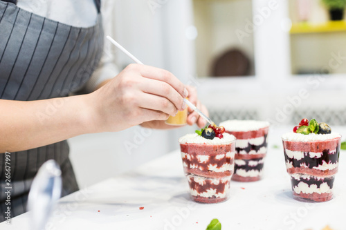 Decoration of the finished dessert. Pastry chef sprinkles confectionery with yellow powder. The concept of homemade pastry  cooking cakes.
