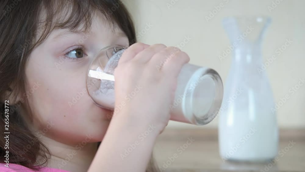 Portrait of a child drinking milk. Charming little girl is drinking milk in the kitchen.