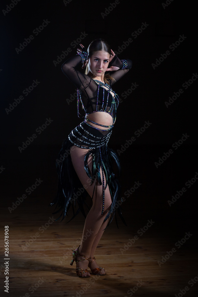 Beautiful Latino dancer girl in elegant black dress on black background