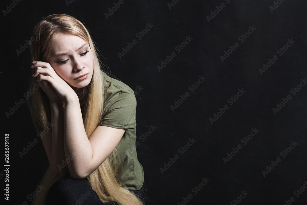 Sad young woman going to cry in a black background Sad young woman going to cry in a black background
