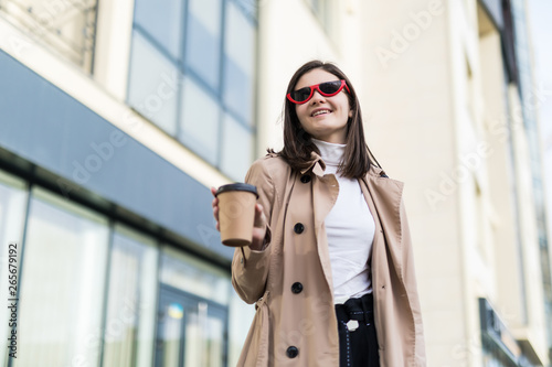 Beautiful young woman in sunglasses and coat with coffee outdoors © dianagrytsku