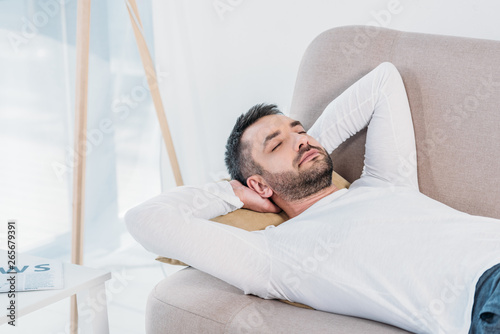 handsome bearded man with eyes closed and Hands Behind Back sleeping on couch at home