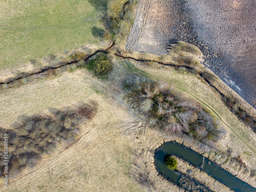 aerial view of small country river bed wavy in spring time in countryside