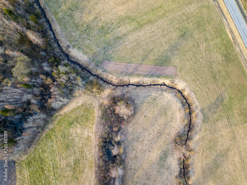 aerial view of small country river bed wavy in spring time in countryside