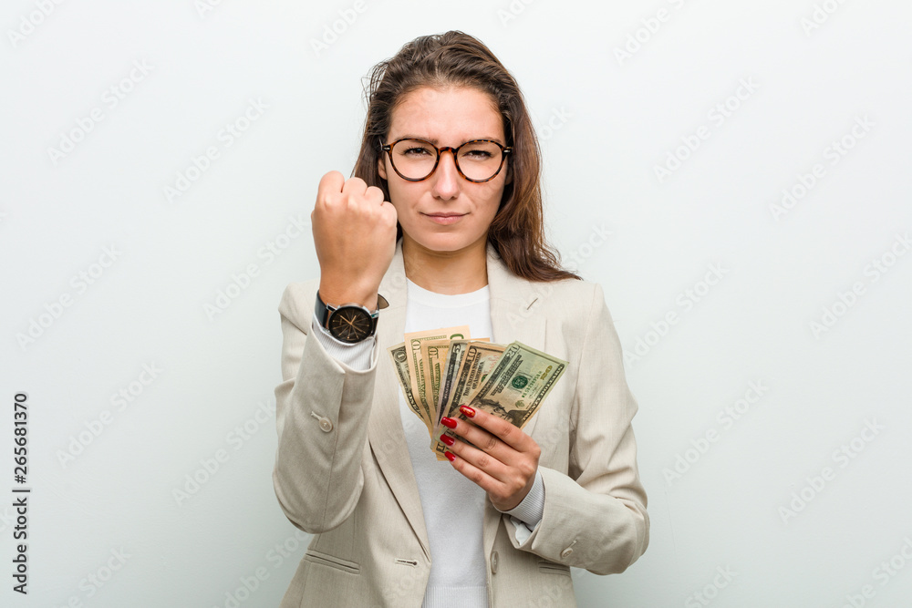 Young european business woman holding dollar banknotes showing fist to camera, aggressive facial expression. Young european business woman holding dollar banknotes showing fist to camera, aggressive facial expression.